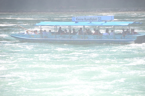 The boat is shrouded in mist, even as it sits relatively far away from Rheinfall