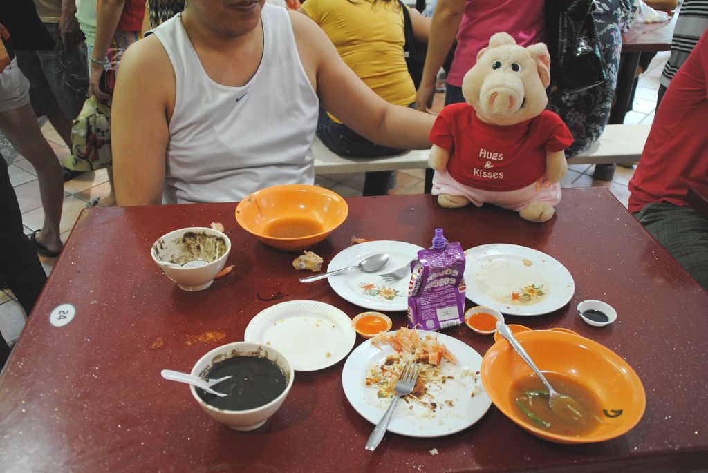 A stuffed pig sitting in front of several different food in Singapore.
